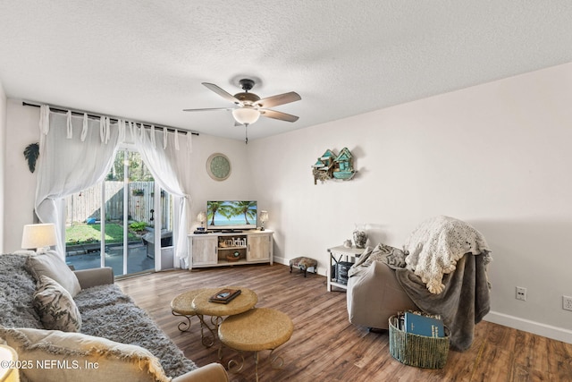 living room with a textured ceiling, hardwood / wood-style floors, and ceiling fan