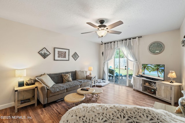 living room featuring hardwood / wood-style flooring, ceiling fan, and a textured ceiling