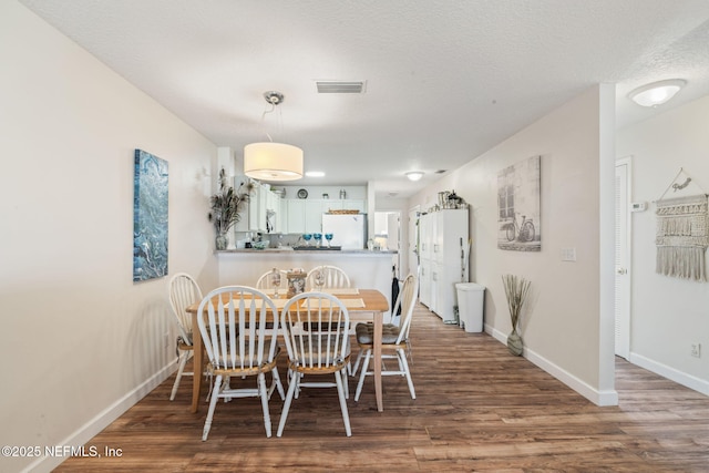 dining area with wood-type flooring and a textured ceiling