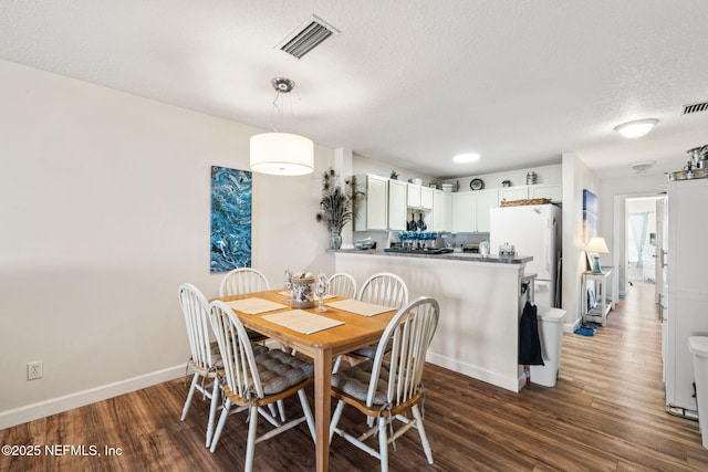 dining space featuring dark wood-type flooring and a textured ceiling