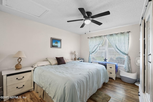 bedroom with ceiling fan, dark hardwood / wood-style flooring, and a textured ceiling