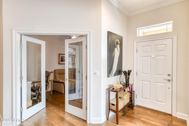 entryway with light hardwood / wood-style floors, french doors, and crown molding