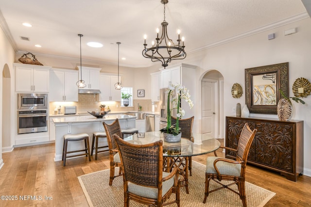 dining room featuring light hardwood / wood-style flooring, crown molding, and an inviting chandelier