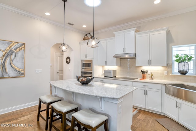 kitchen with white cabinets, stainless steel appliances, a kitchen island, and decorative light fixtures