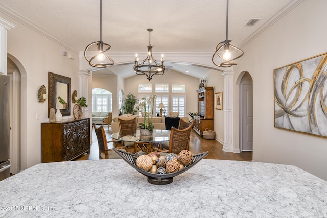 dining area featuring lofted ceiling, decorative columns, a notable chandelier, dark hardwood / wood-style floors, and ornamental molding