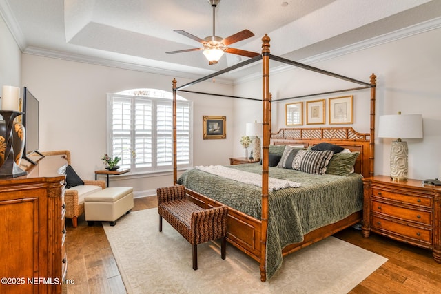 bedroom featuring hardwood / wood-style flooring, a raised ceiling, and crown molding