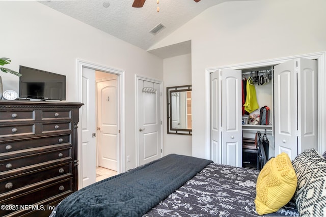 bedroom with vaulted ceiling, ceiling fan, a closet, and a textured ceiling