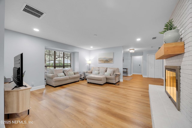 living area featuring light wood-type flooring, a fireplace, visible vents, and recessed lighting