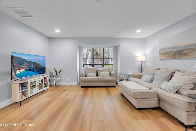 living room featuring a textured ceiling, recessed lighting, visible vents, baseboards, and light wood-style floors