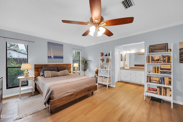 bedroom with visible vents, baseboards, light wood finished floors, ensuite bath, and crown molding