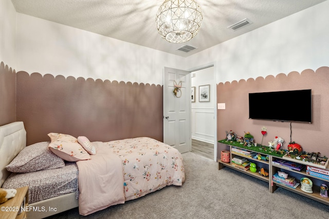 carpeted bedroom with visible vents, a notable chandelier, and a textured ceiling