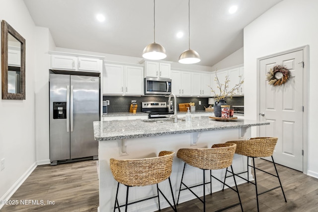 kitchen featuring appliances with stainless steel finishes, white cabinets, a sink, and light stone counters