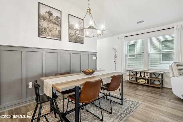 dining room featuring a decorative wall, visible vents, and light wood-style floors