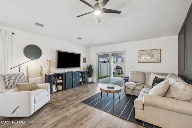 living room featuring wood finished floors, visible vents, and a ceiling fan