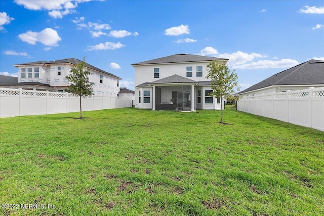 rear view of property featuring a sunroom and a lawn