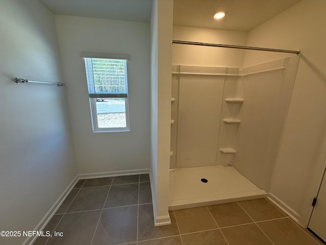 full bath with baseboards, walk in shower, and tile patterned flooring
