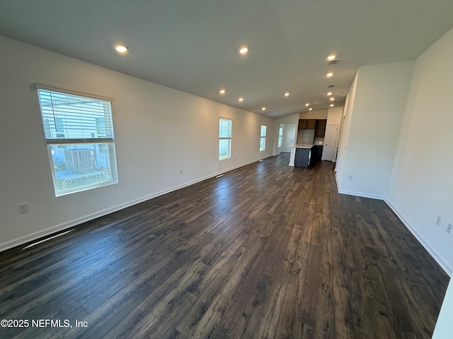 unfurnished living room featuring recessed lighting, baseboards, dark wood-type flooring, and lofted ceiling