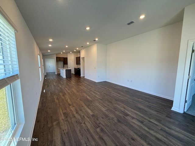 unfurnished living room with dark wood-style floors, visible vents, baseboards, lofted ceiling, and recessed lighting