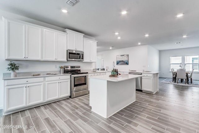 kitchen featuring stainless steel appliances, light countertops, visible vents, white cabinets, and a kitchen island