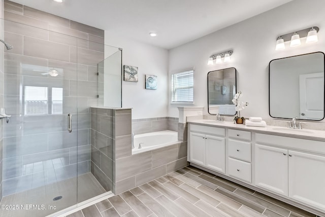 bathroom with a stall shower, a garden tub, a sink, and double vanity