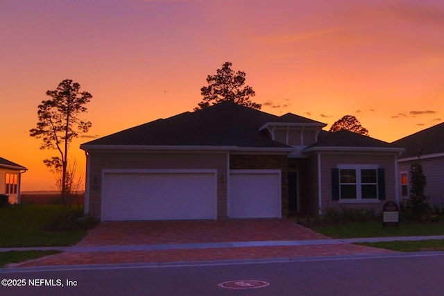 view of front of property with a garage, decorative driveway, and a front yard