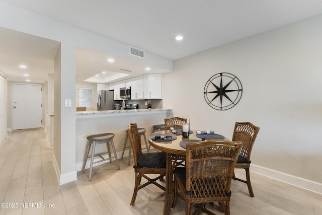 dining room featuring light wood-type flooring, visible vents, recessed lighting, and baseboards