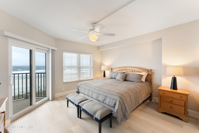 bedroom featuring baseboards, light wood-style flooring, access to outside, and a water view