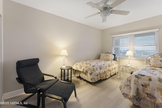 bedroom with a ceiling fan, baseboards, and light wood-type flooring