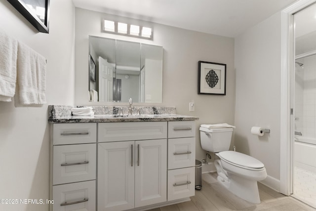 bathroom with vanity, toilet, baseboards, and shower / bathing tub combination