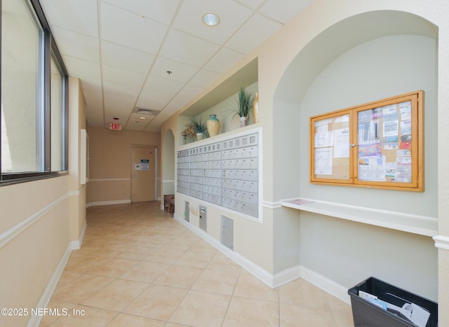 hallway with baseboards, visible vents, mail area, a paneled ceiling, and light tile patterned floors