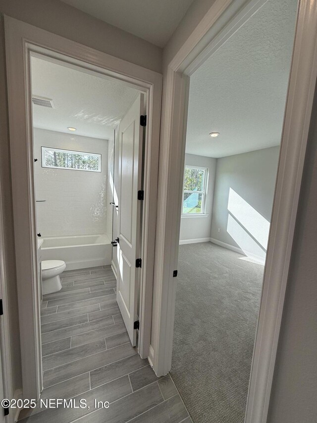 15 Wimbledon Way, Palm Coast, FL 32164 - full bathroom featuring baseboards, visible vents, wood tiled floor, a textured ceiling, and toilet