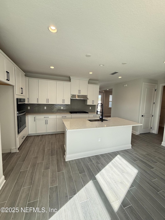 15 Wimbledon Way, Palm Coast, FL 32164 - kitchen with under cabinet range hood, black stovetop, wood finish floors, and a sink