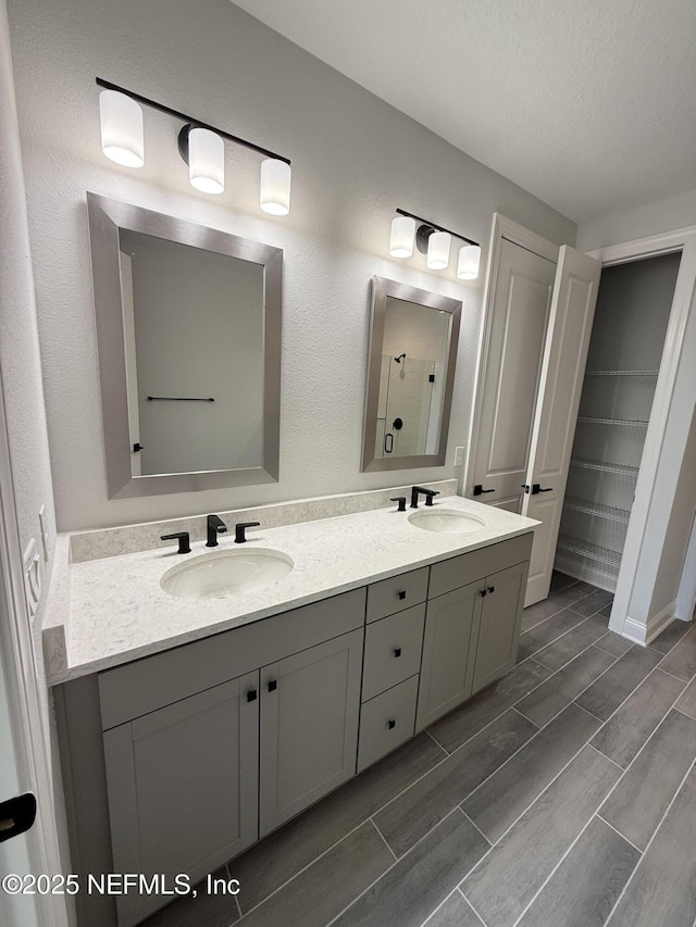 15 Wimbledon Way, Palm Coast, FL 32164 - bathroom featuring a sink, a shower, wood tiled floor, and double vanity