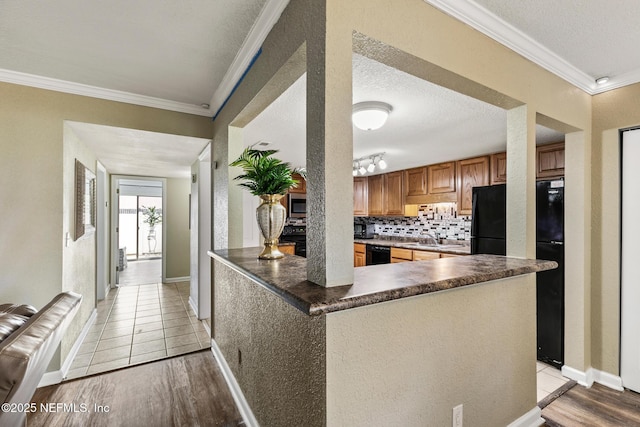 kitchen featuring tasteful backsplash, light wood-style floors, crown molding, and dark countertops