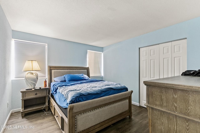 bedroom with a textured ceiling, a closet, baseboards, and wood finished floors