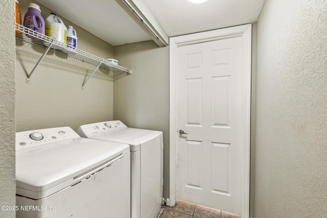 clothes washing area featuring washing machine and dryer, laundry area, a textured wall, and light tile patterned floors