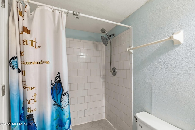 bathroom featuring toilet, tiled shower, and a textured wall