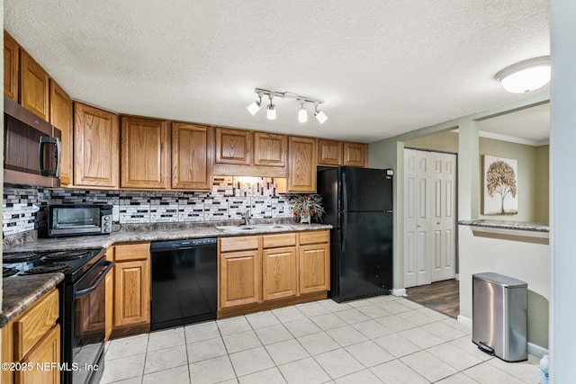 kitchen featuring black appliances, a toaster, brown cabinetry, and a sink