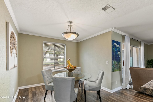 dining space with a textured ceiling, wood finished floors, visible vents, and crown molding