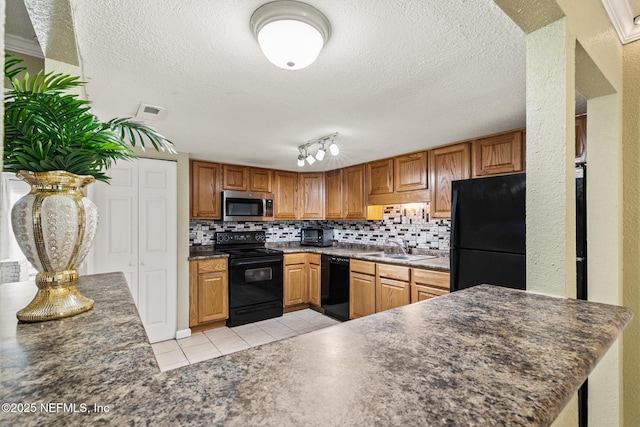 kitchen featuring light tile patterned floors, a sink, black appliances, tasteful backsplash, and dark countertops