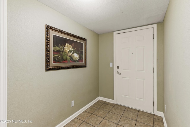 entryway featuring tile patterned flooring, baseboards, and a textured ceiling