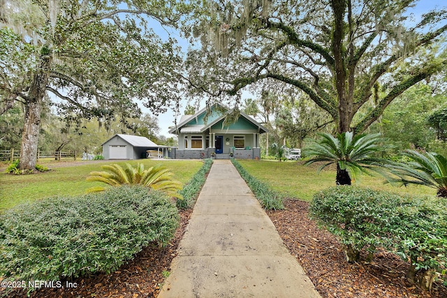 view of front of home with a porch, a detached garage, an outdoor structure, driveway, and a front lawn