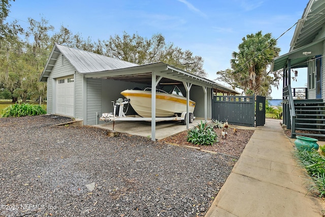 view of property exterior featuring an outbuilding, metal roof, a carport, and a detached garage