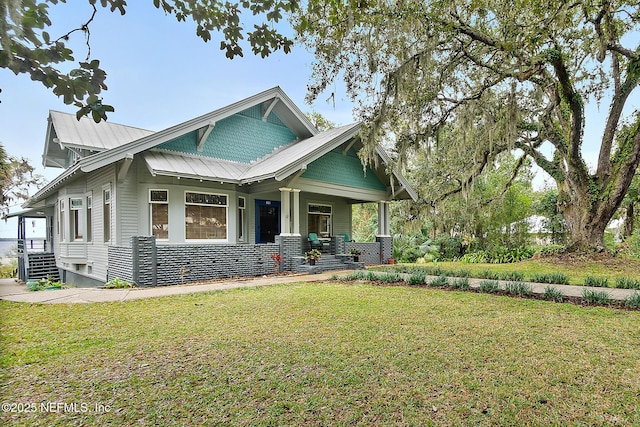 view of front of home with covered porch, metal roof, a standing seam roof, and a front yard