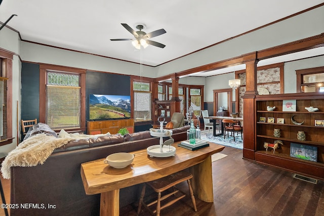 living area with dark wood finished floors, decorative columns, visible vents, ornamental molding, and plenty of natural light