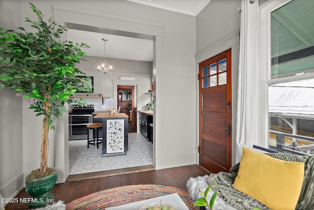 entryway featuring a chandelier, ornamental molding, wood finished floors, and baseboards