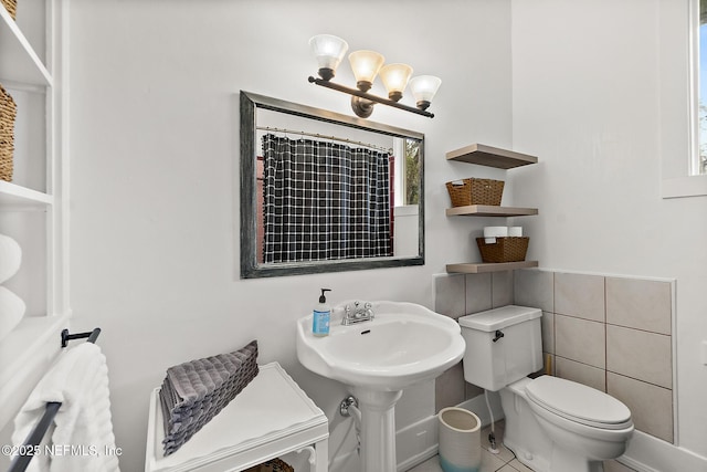 full bathroom with curtained shower, a sink, toilet, and an inviting chandelier