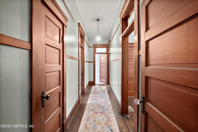 corridor featuring dark wood-type flooring and baseboards