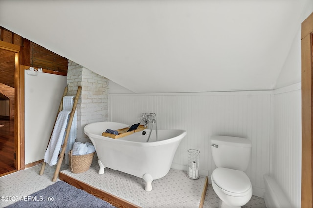 bathroom featuring a soaking tub, vaulted ceiling, and toilet