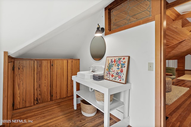 interior space with lofted ceiling, a sink, and wood finished floors